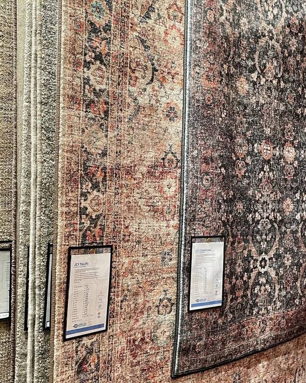 Rugs with size and price cards on the showroom rug rack