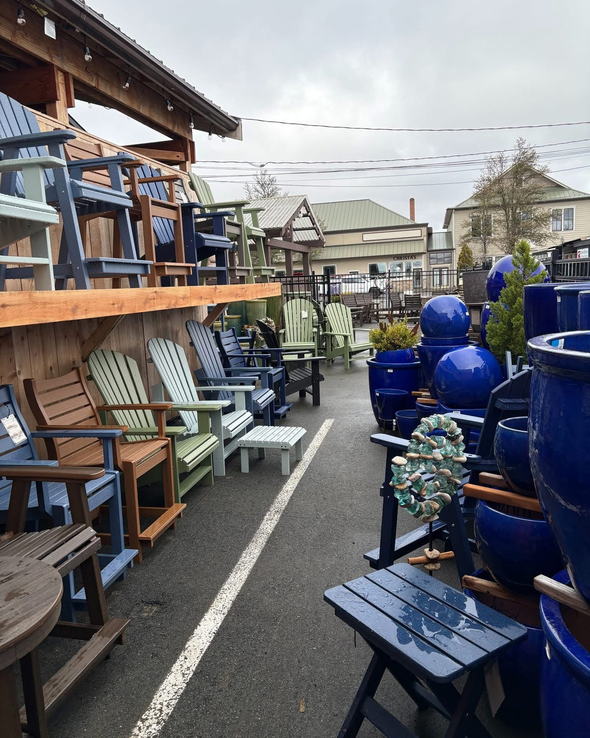 Rows of colorful Adirondack and patio chairs beside cobalt-blue glazed outdoor pots and fountains in the Over the Fence outdoor yard